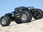 A black monster truck is parked on the beach.